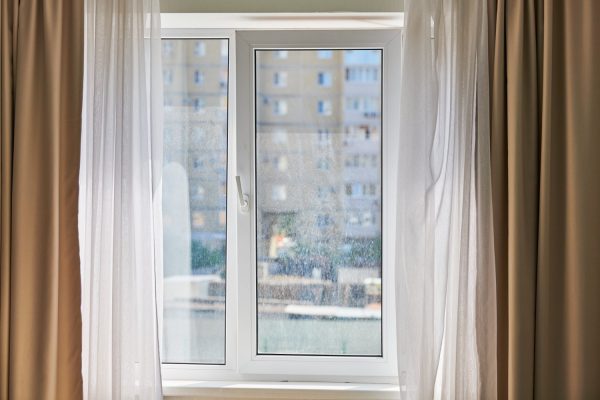 Dirty window in apartment. Unwashed dusty glass, city street view background. Unclean double glazed window